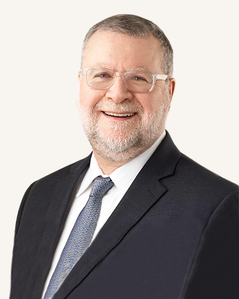 A smiling man in business attire over a light background.