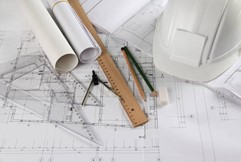 Overhead shot of architectural tools. A hat, some blueprints, and some drawing tools are visible.