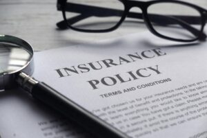 insurance policy document with magnifying glass and reading glasses.