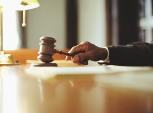 Hand and arm of a court Judge hitting block on his bench with a gavel.