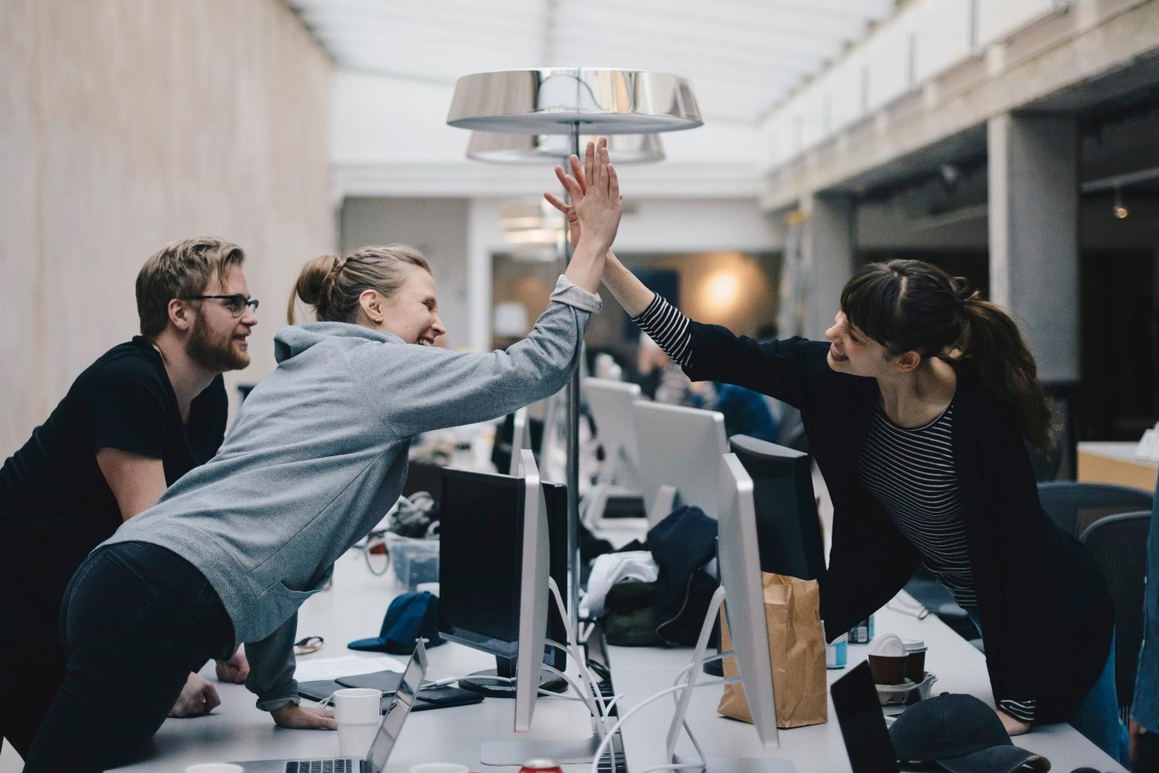 Team doing a high-five over their workspaces.