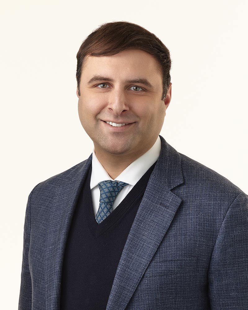 Man in a navy suit with a blue tie
