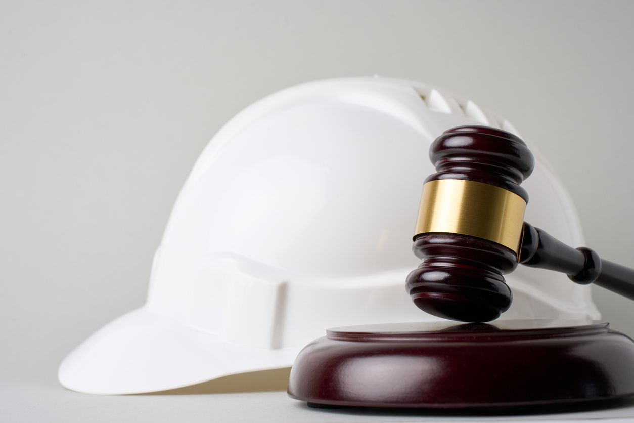 Judge's gavel in the front with white hard hat in the back.